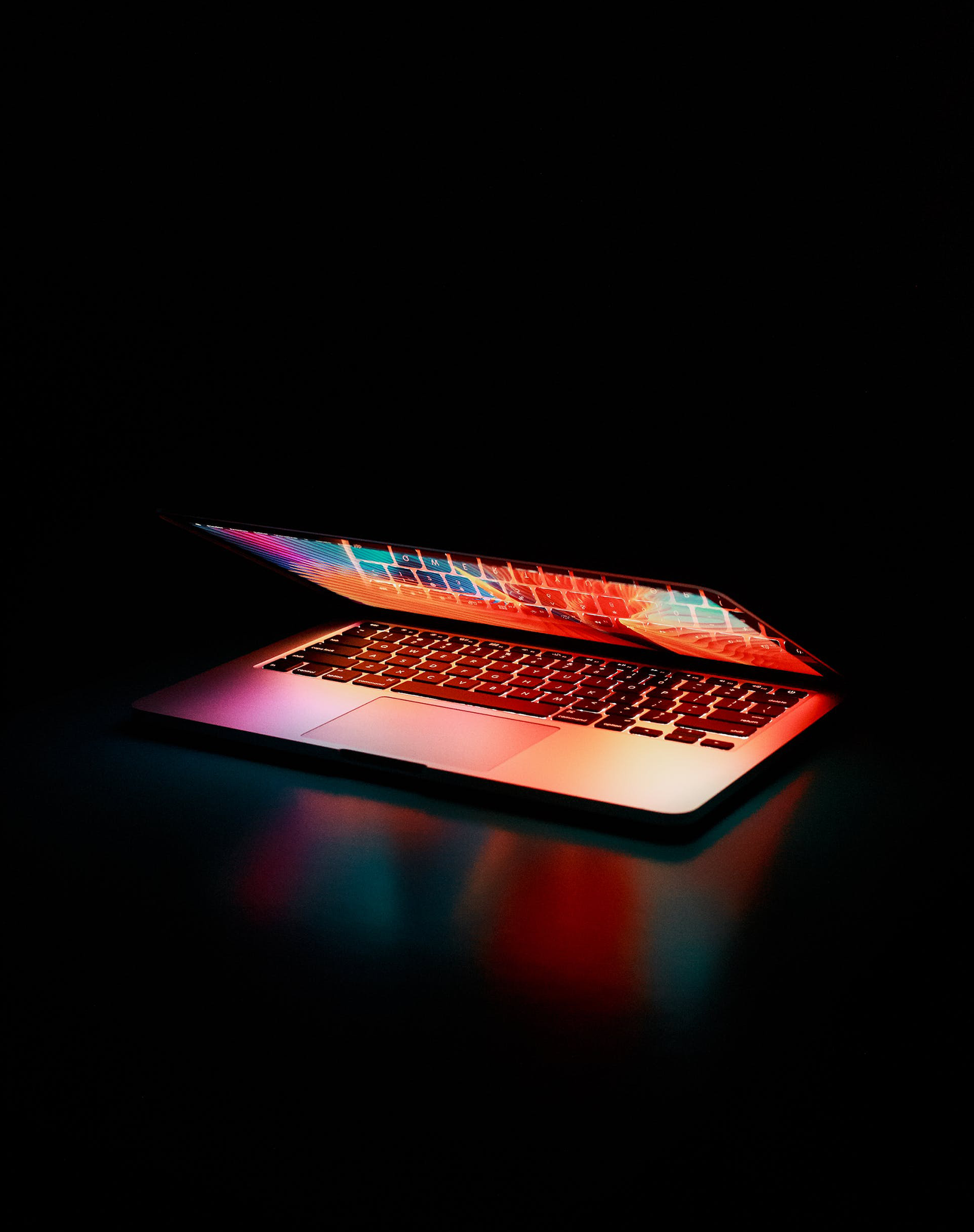 A MacBook half closed in a dark setting