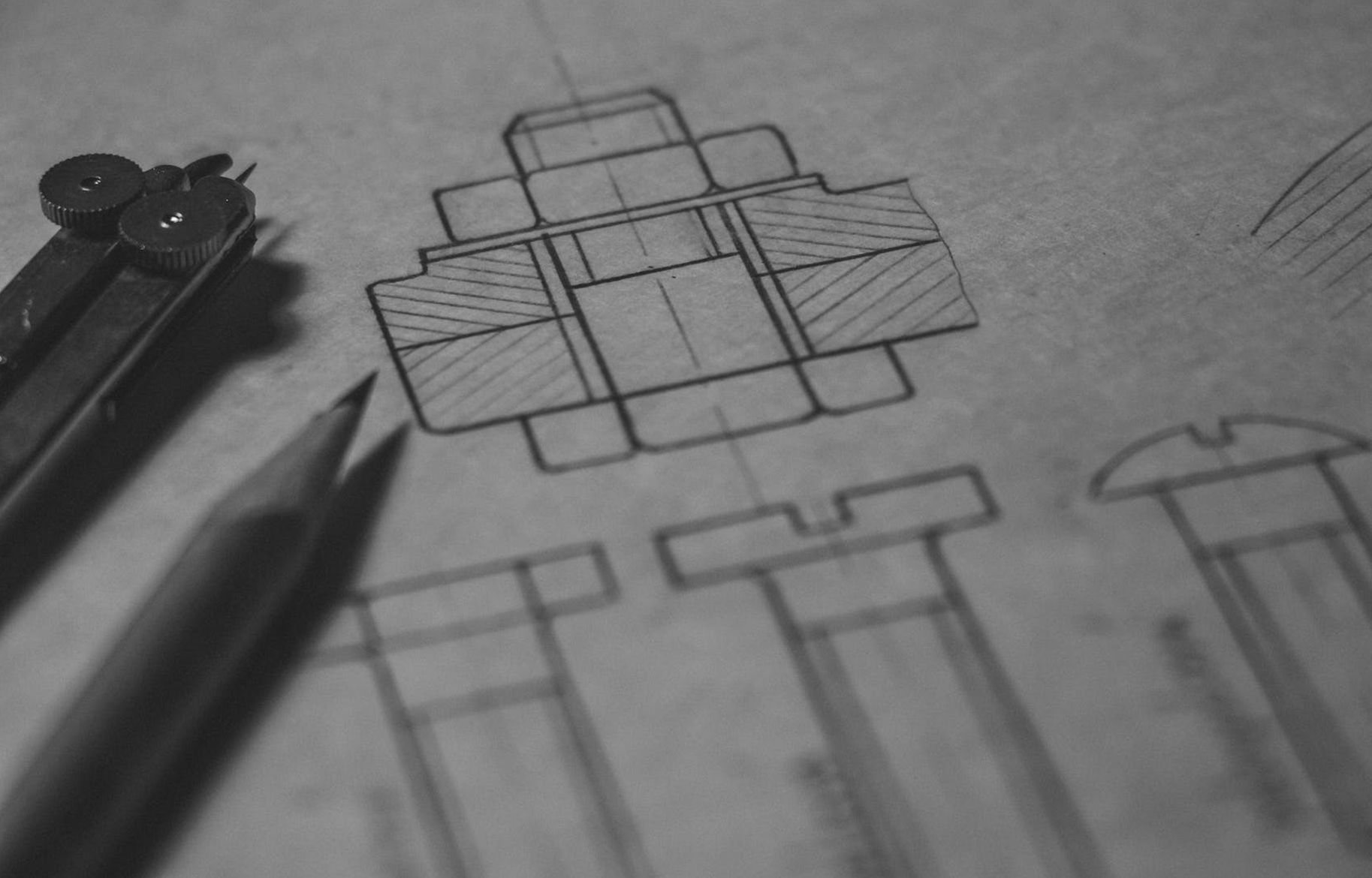 A pencil and a pair of compasses on top of a sketch