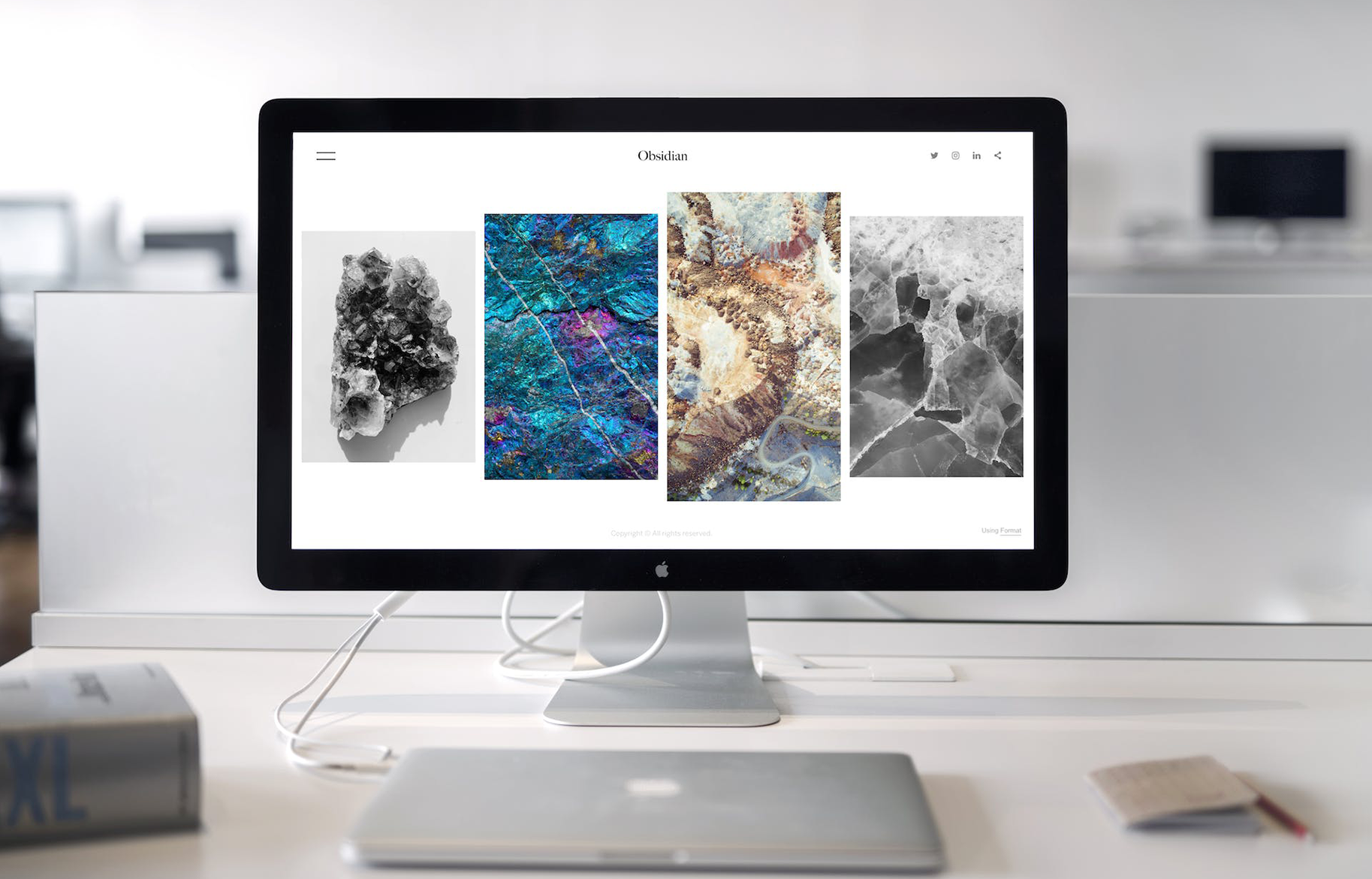 An Apple MacBook displaying a website made using frontend code through an Apple Thunderbolt Display